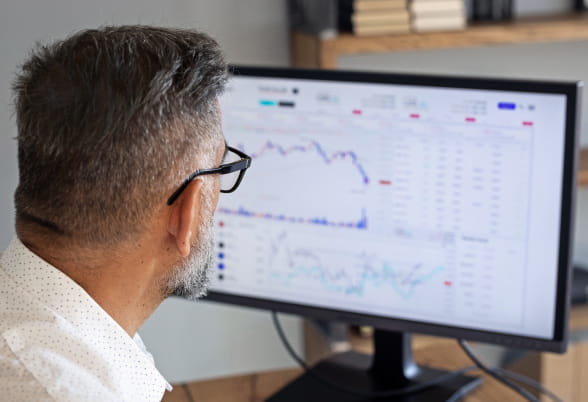 Professional trader intently analyzing financial data on a computer screen, exemplifying StoneX's diverse financial trading capabilities: spot trading, margin facilities, forward contracts, options, location swaps, leases, consignment accounts, hedging structures, and API trading